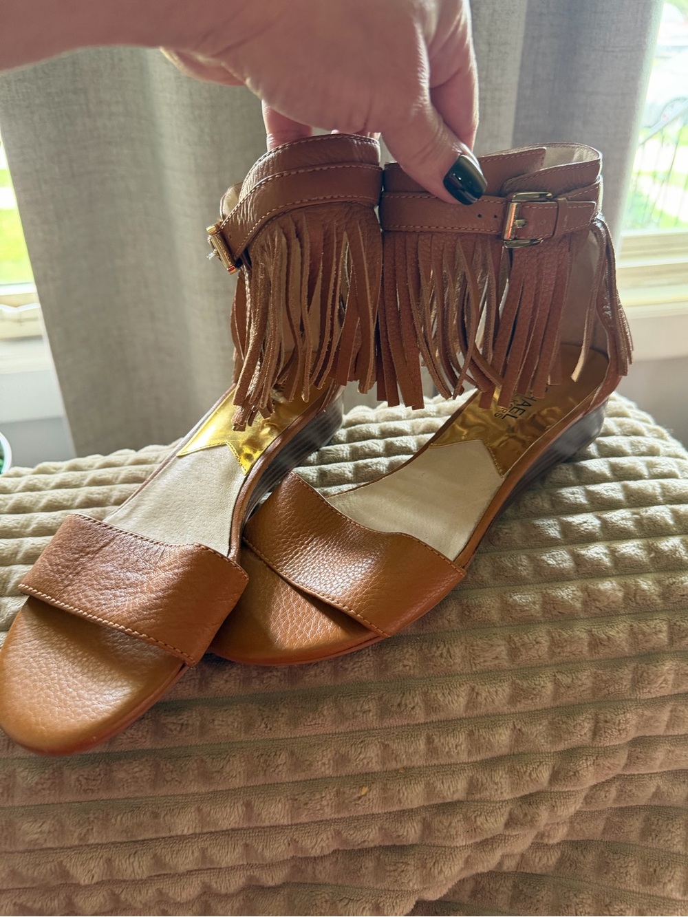 These are Michael Kors tan leather fringe sandals with a gold-tone logo buckle